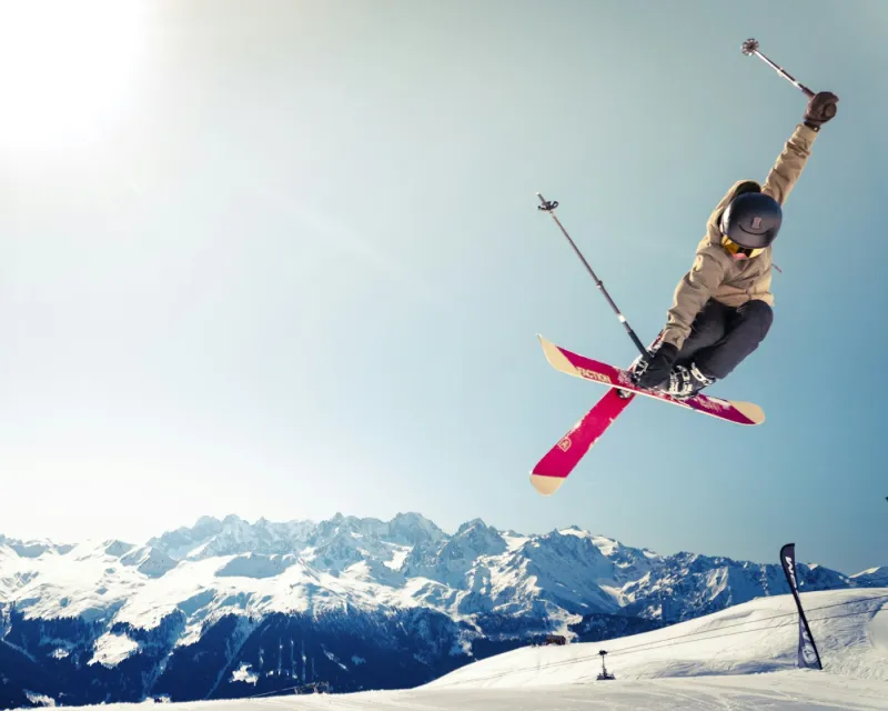 A skier jumping against a snowy mountain backdrop