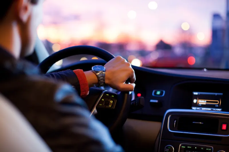A professional chauffeur at the wheel at dusk